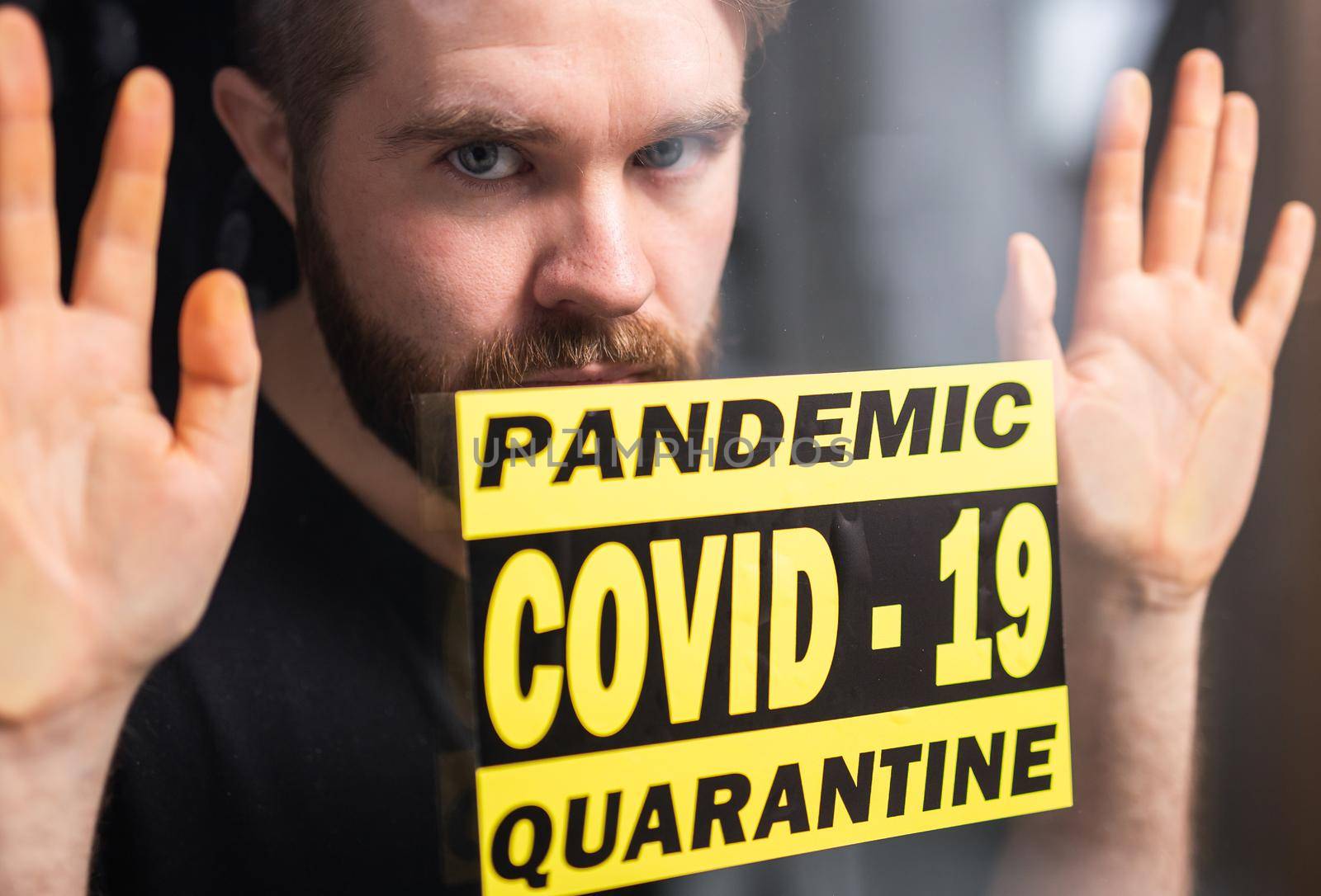 Coronavirus, quarantine, covid-19 and pandemic concept. Sad and sick man of corona virus looking through the window. Stay at home. by Satura86