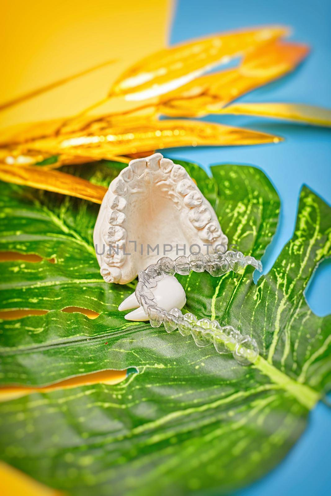 Orthodontic dental theme on blue and yellow background.Transparent invisible dental aligners or braces aplicable for an orthodontic dental treatment