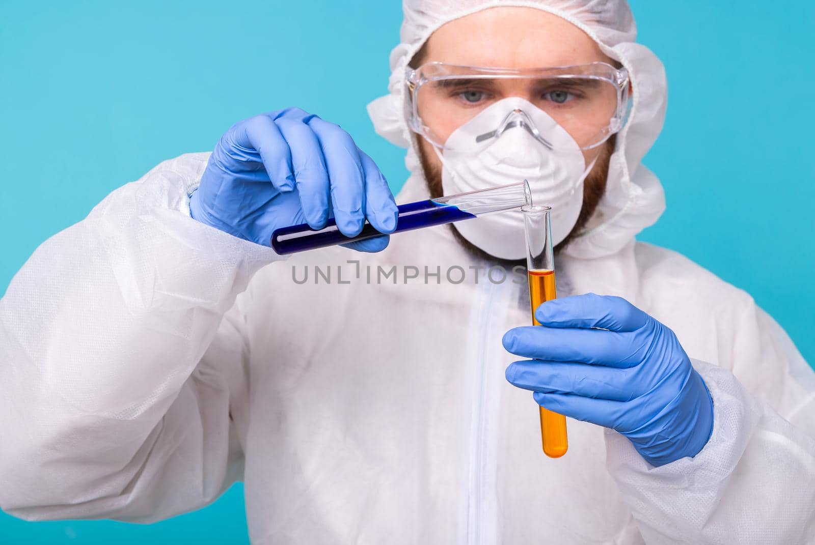Covid-19, Vaccine development, pandemic, outbreak and coronavirus concept - Man scientist dressed personal protective equipment holding a test tube and does a chemical experiment. by Satura86