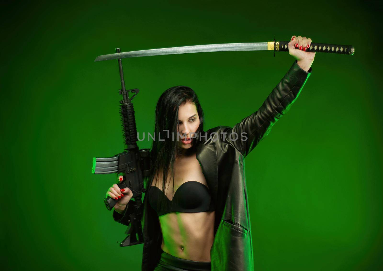 the slender woman in a black leather raincoat with an American automatic rifle and a katana on a green background
