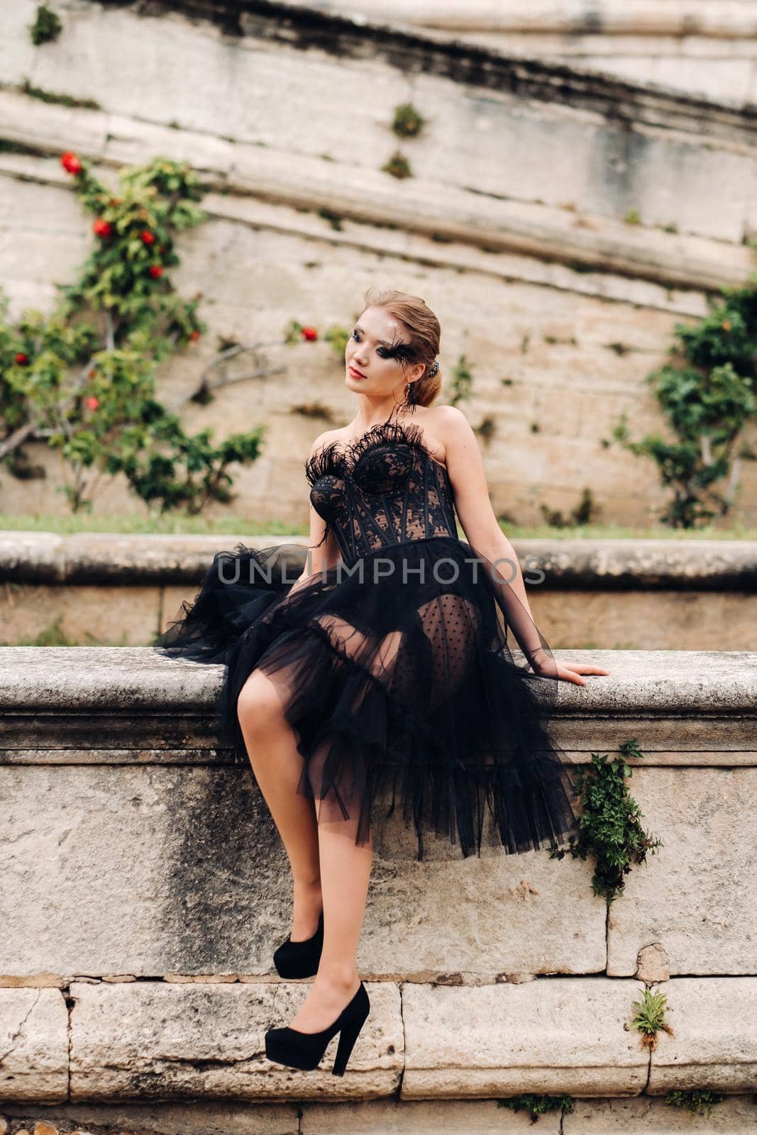 A stylish bride in a black wedding dress poses in the ancient French city of Avignon. Model in a beautiful black dress. Photo shoot in Provence