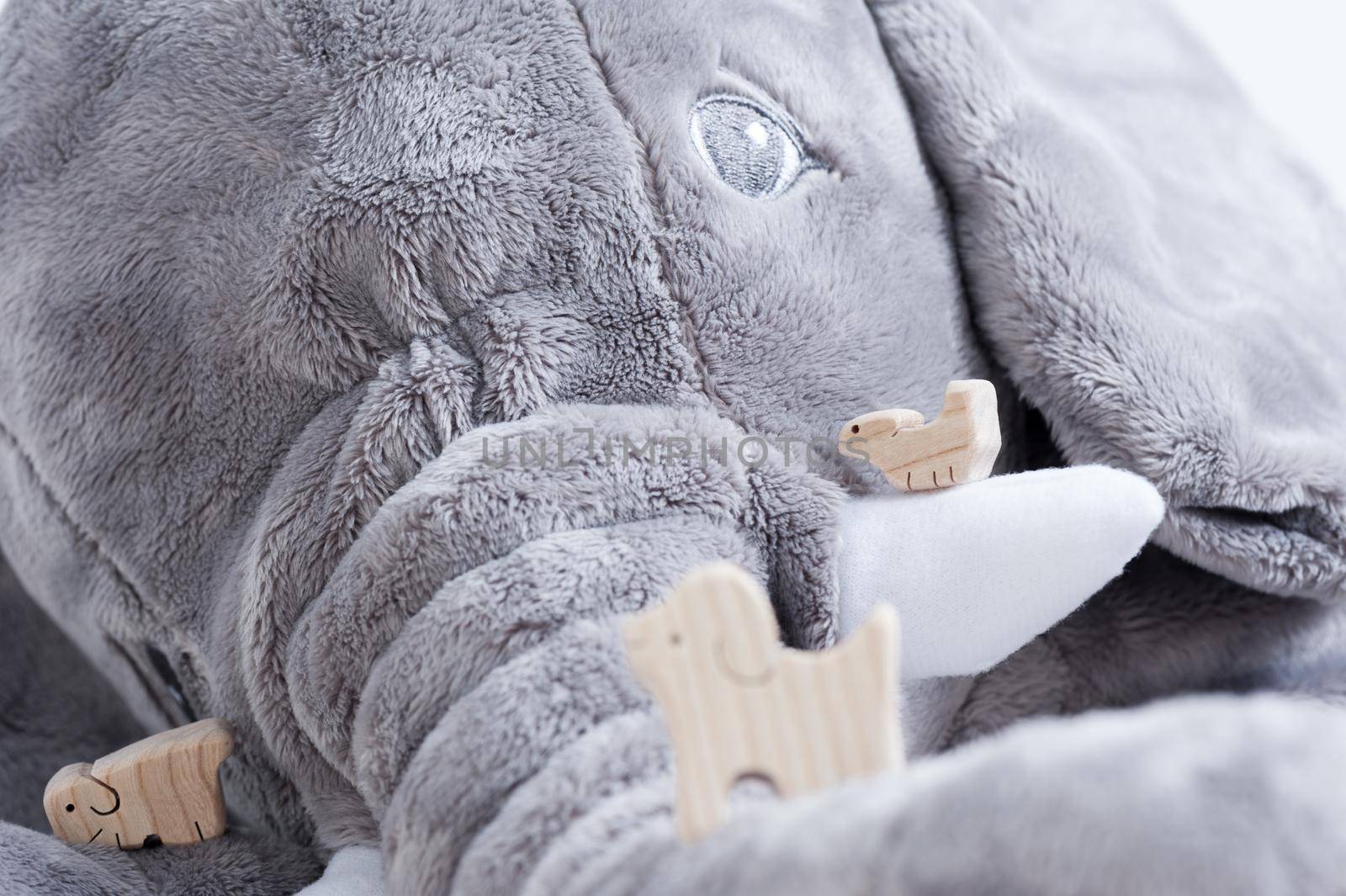 cute wooden toy animals on white wood plank with giant elephant doll in the background, tiny toys and shallow depth of field