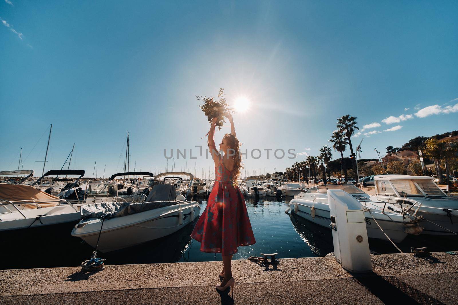 Young model girl in a beautiful dress with a bouquet of flowers on the beach in France. Girl with flowers in spring Provence on the French Riviera.