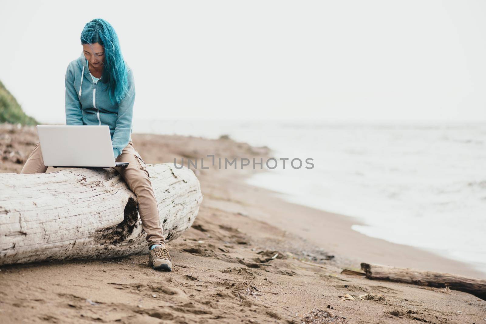 Freelancer woman sitting on beach and working on laptop near the sea. Freelance concept.