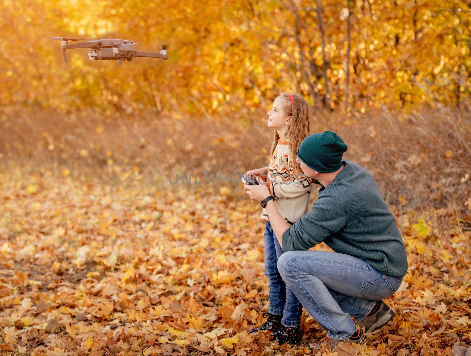 Father and daughter launch quadrocopter in autumn park