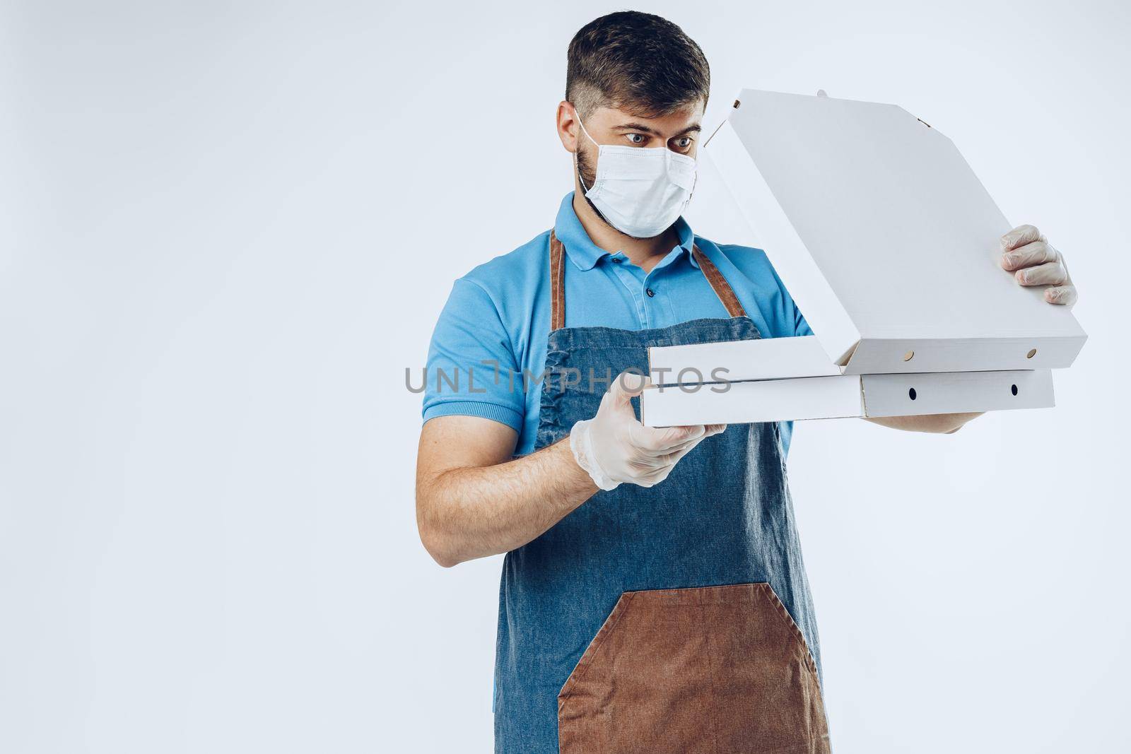 Pizza delivery man in medical gloves and mask against grey background. Safe service while coronavirus covid-19 outbreak
