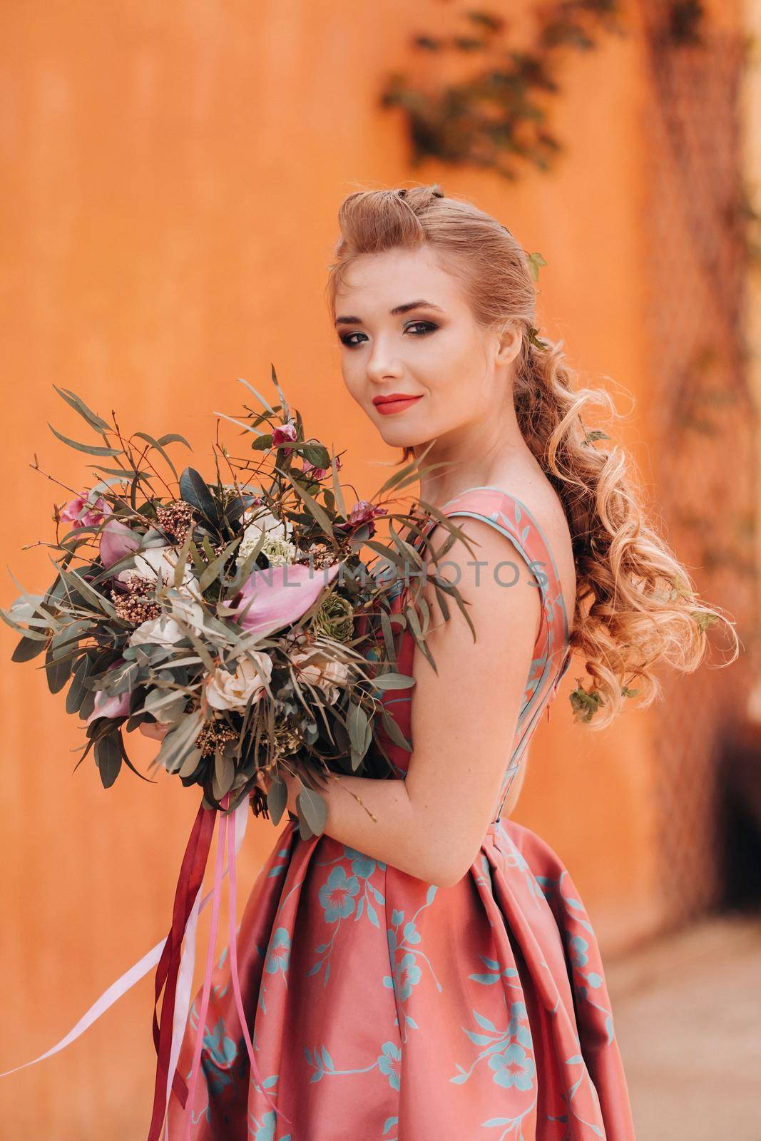 A young model girl in a beautiful dress with a bouquet of flowers in the countryside in France. Girl with flowers in the spring Provence village