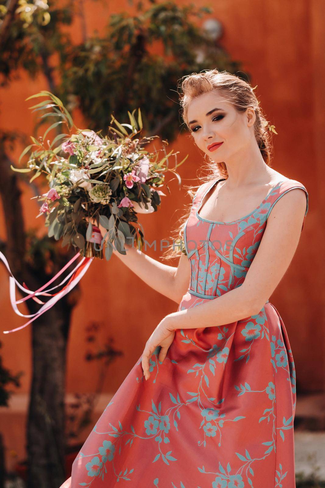 A young model girl in a beautiful dress with a bouquet of flowers in the countryside in France. Girl with flowers in the spring Provence village