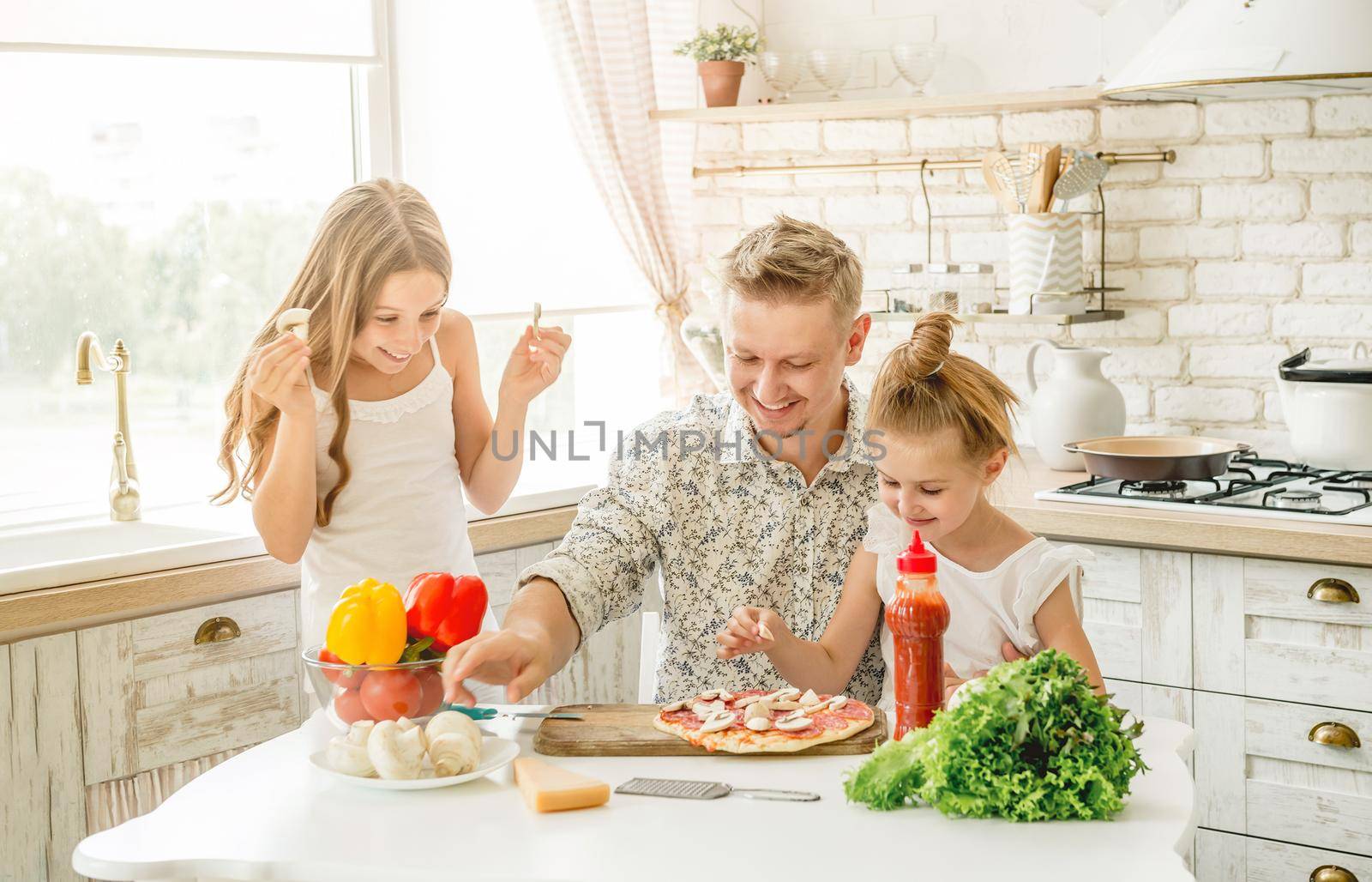 Dad with two small daughters preparing pizza with mushrooms in the kitchen