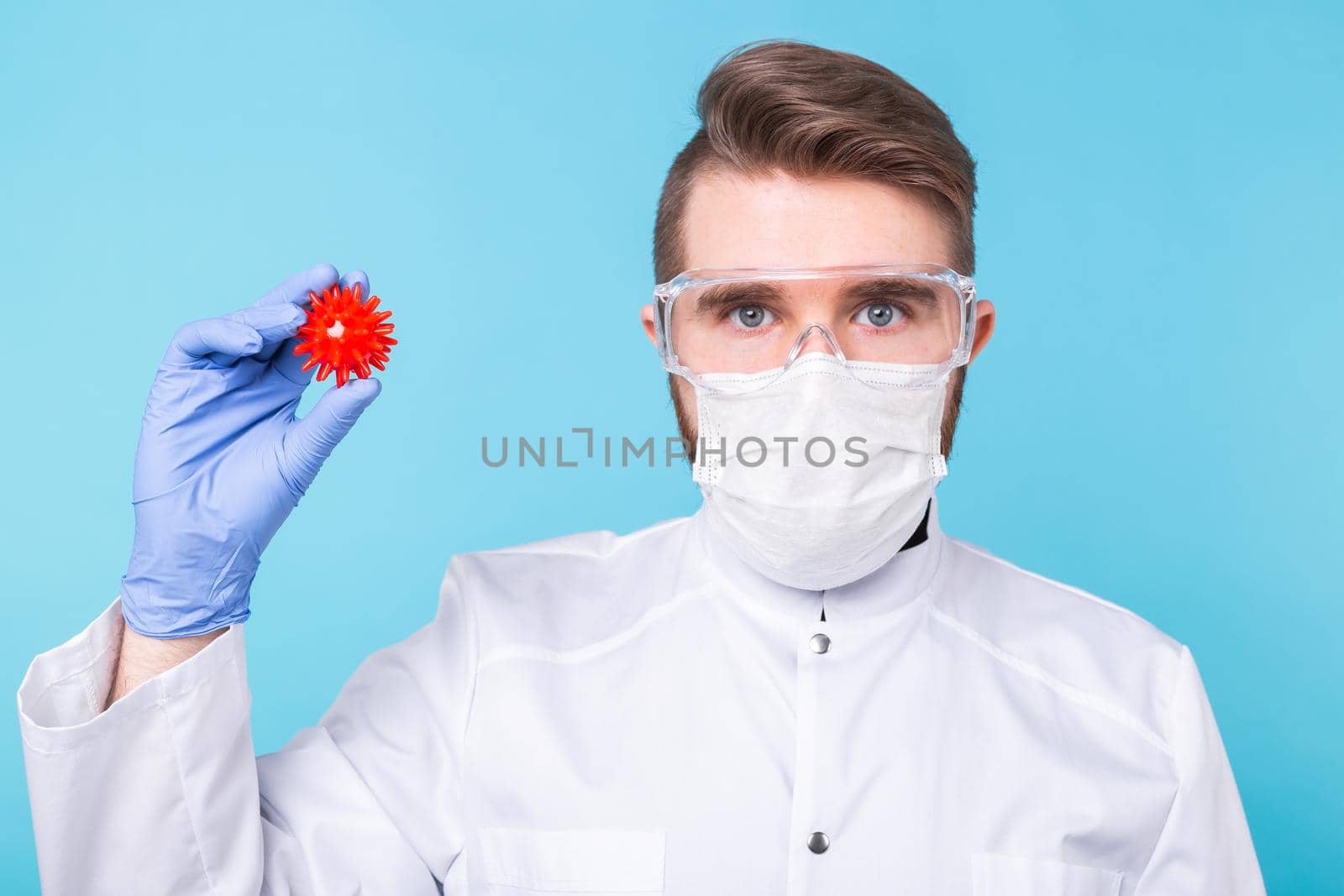 Covid-19, Vaccine development concept - Man scientist in flu mask and protective gloves holding a model of coronavirus