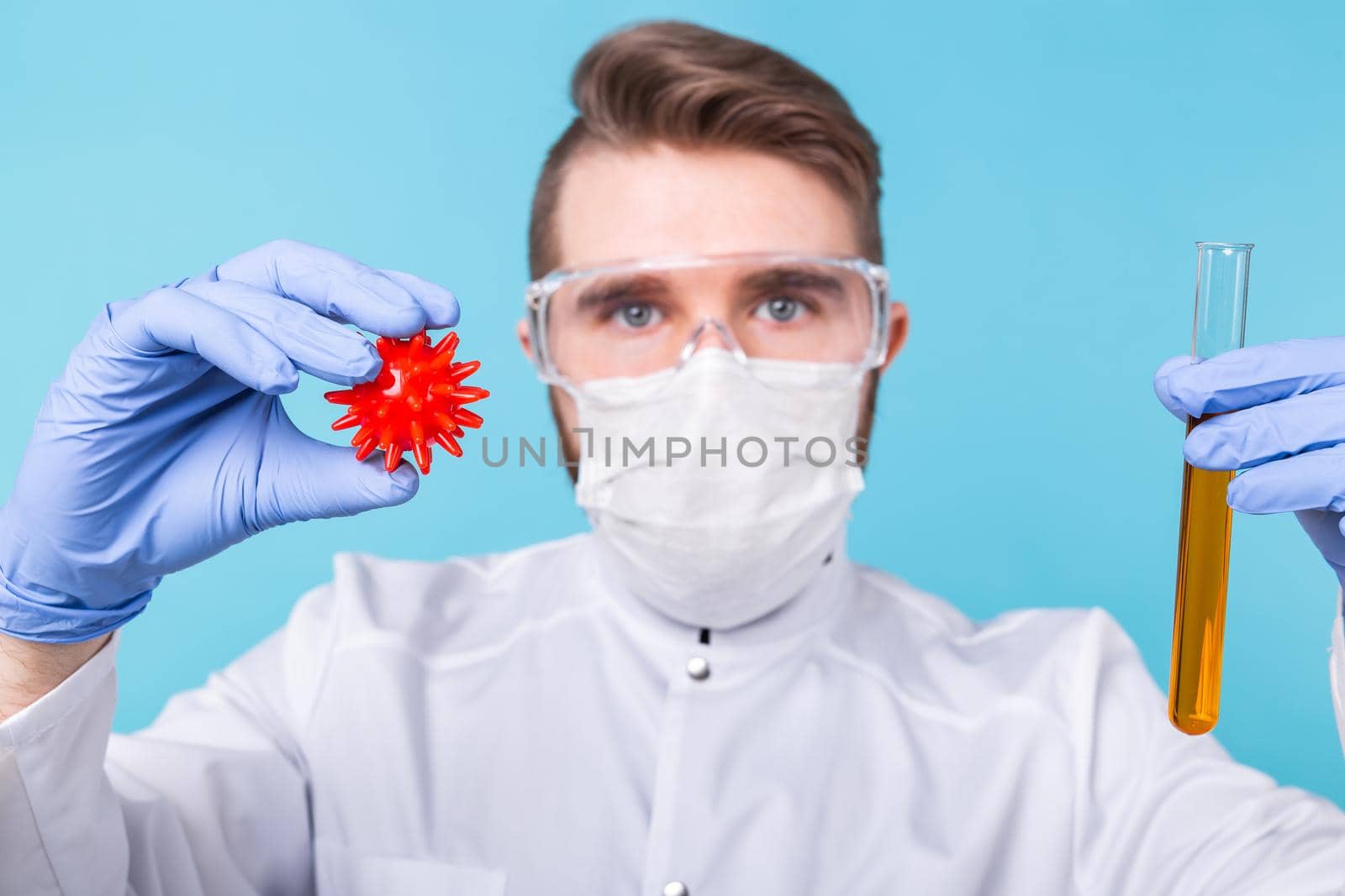 Covid-19, Vaccine development and medicine concept - Man scientist in flu mask and protective gloves holding a model of coronavirus and test tube. by Satura86