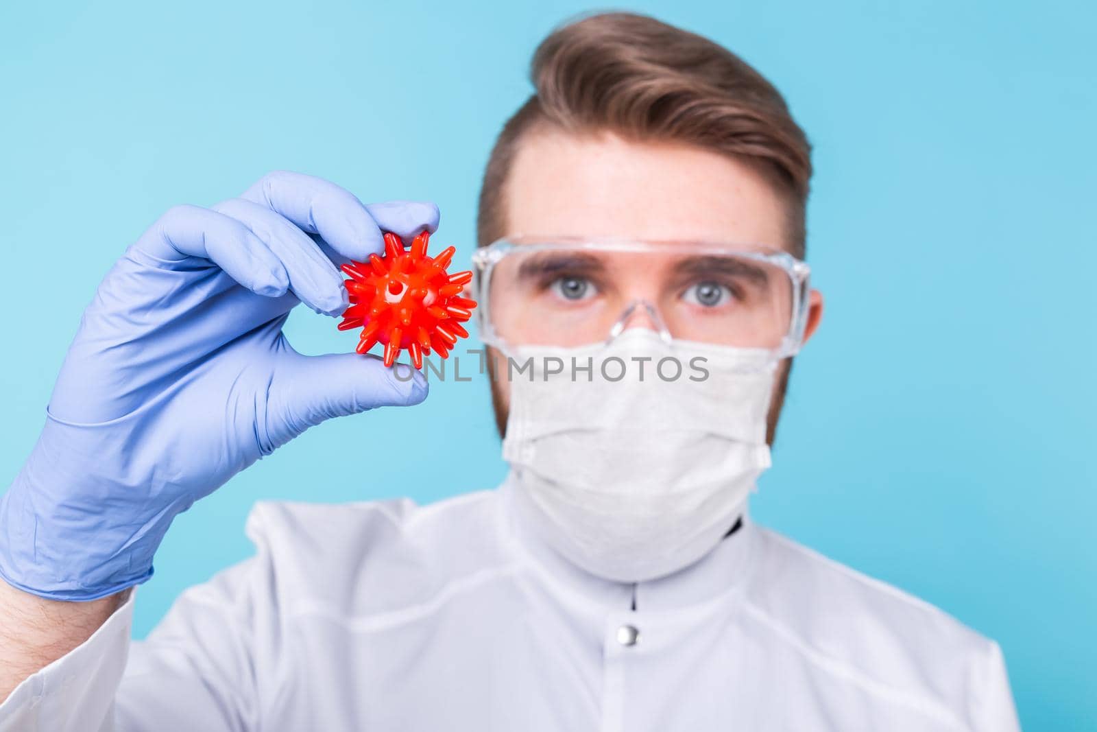 Covid-19, Vaccine development concept - Man scientist in flu mask and protective gloves holding a model of coronavirus