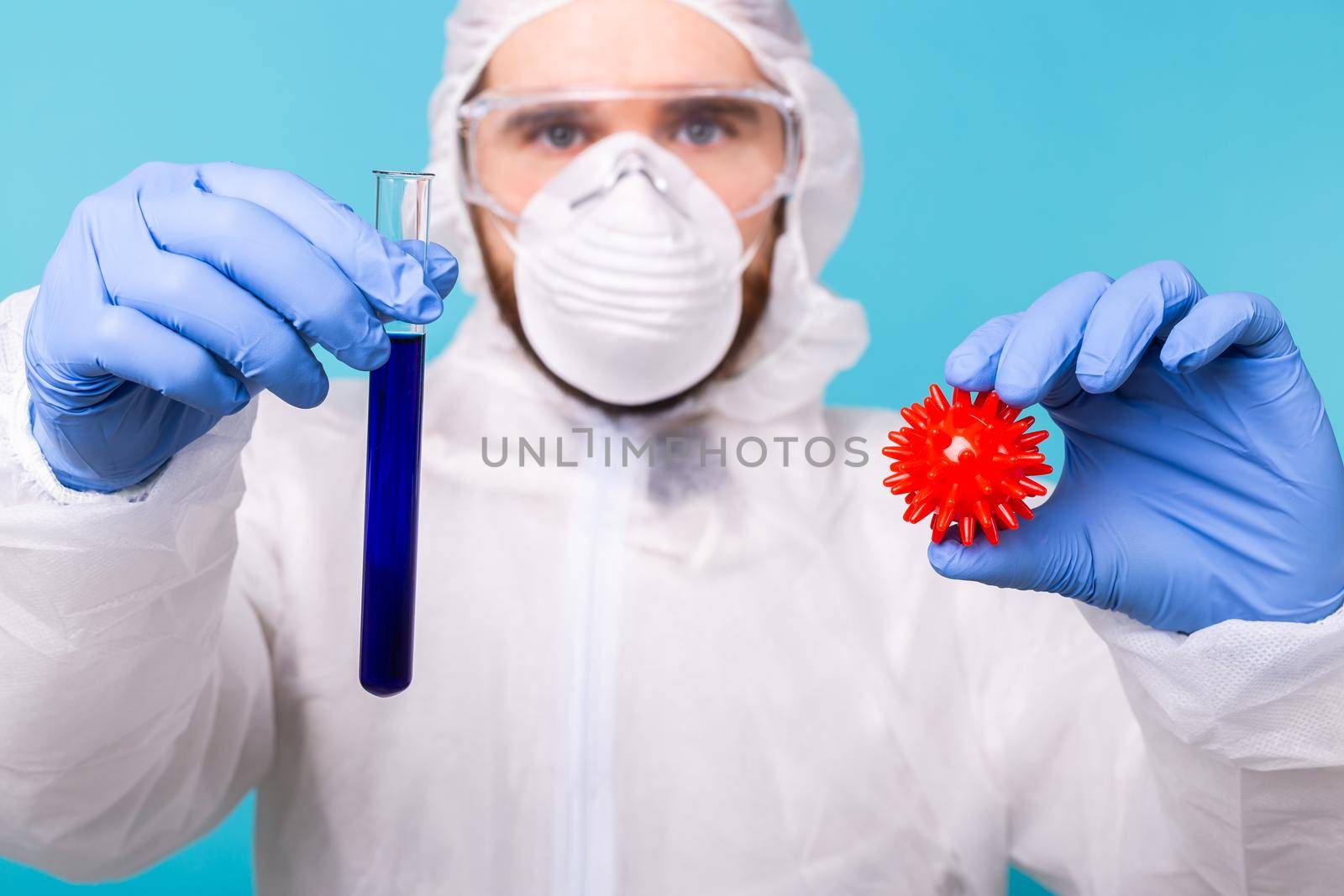 Covid-19, Vaccine development and medicine concept - Man scientist wears personal protective equipment and holding a model of coronavirus