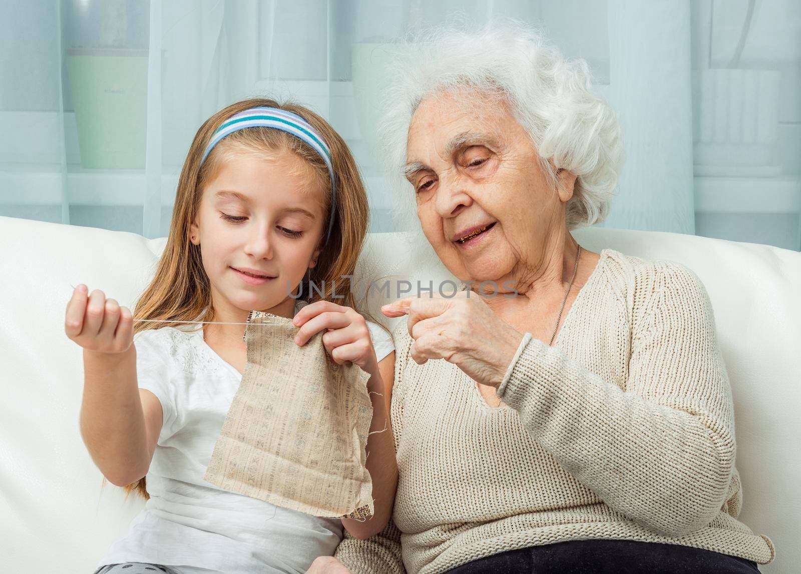 ganddaughter learning to embroider with granny on sofa