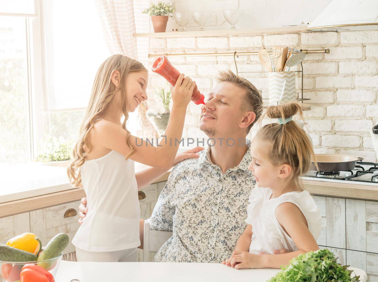 dad with two little daughters have a fun in the kitchen