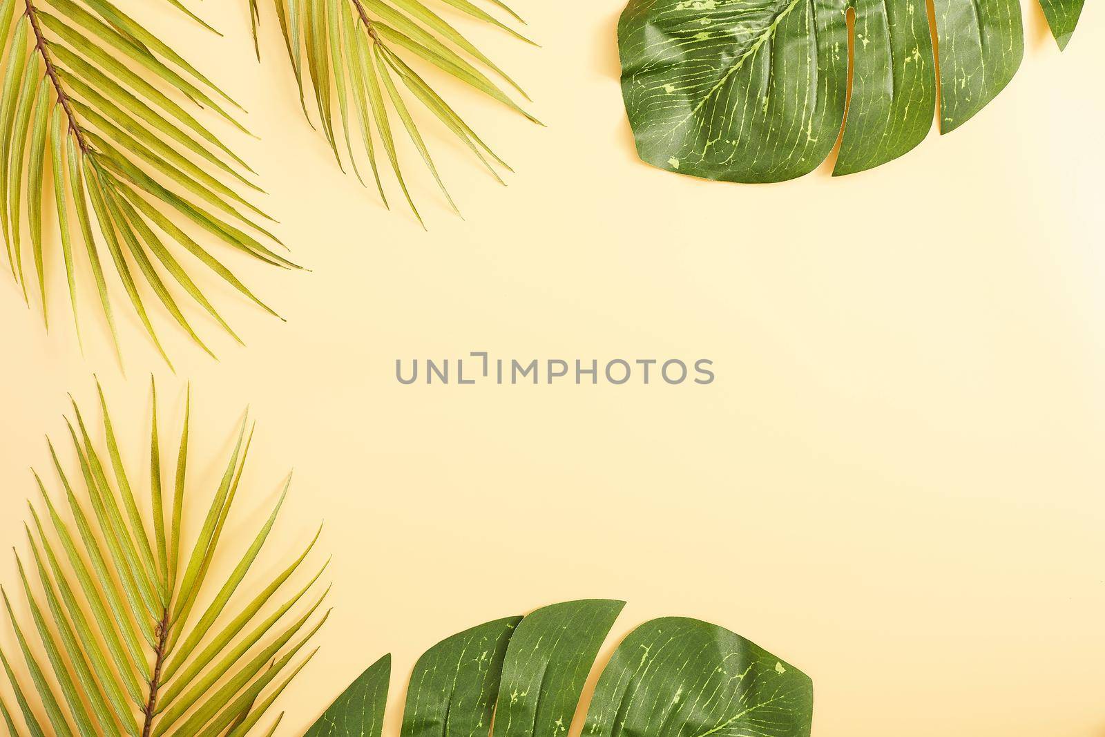 Flat lay, top view, copy space . Tropical palm leaves on yellow background.