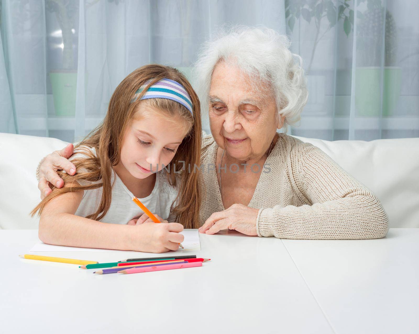 portrait of little girl with grandmother drawing with pencils