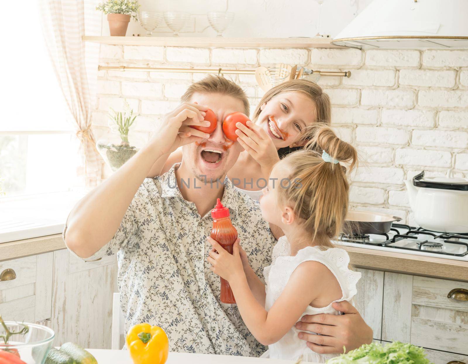 dad with two little daughters have a fun in the kitchen