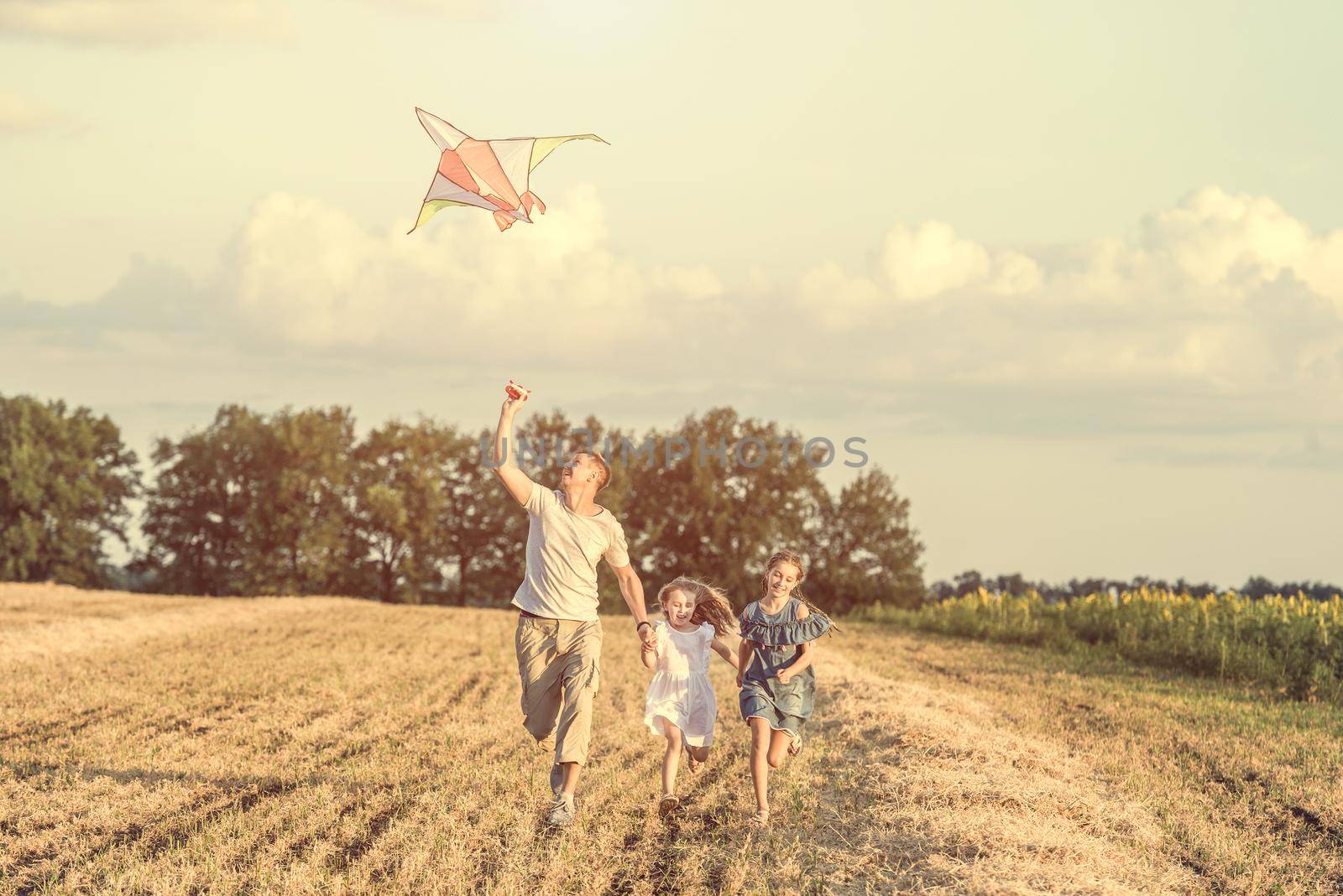 Dad with his little daughters let a kite in a field