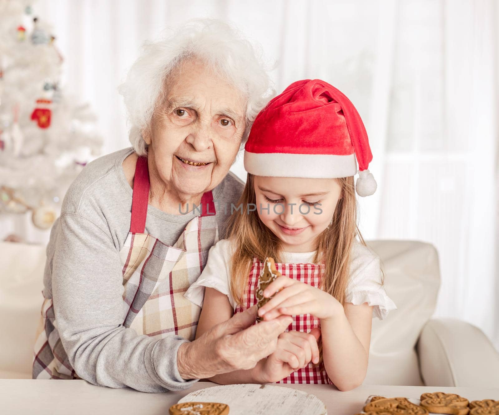 Grandmother with granddaughter holding baked cookie by tan4ikk1