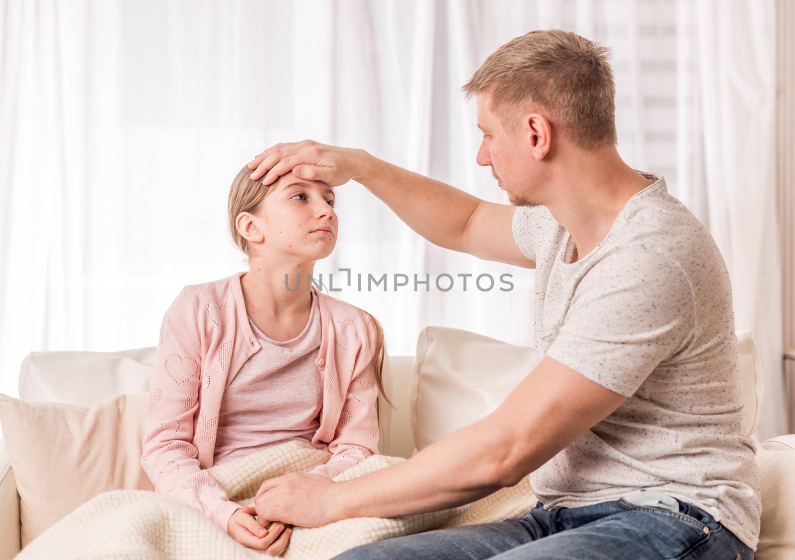 Loving father is checking temperature of sick girl with chickenpox