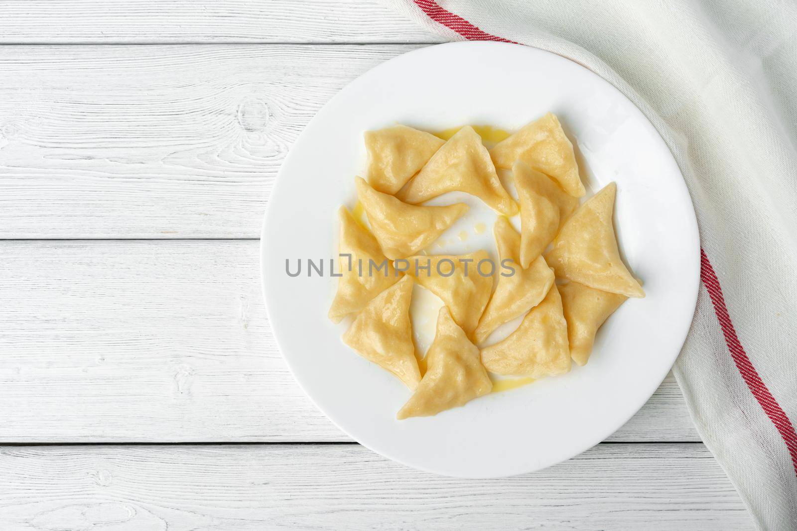 Russian dumplings on white plate on white wooden table close up