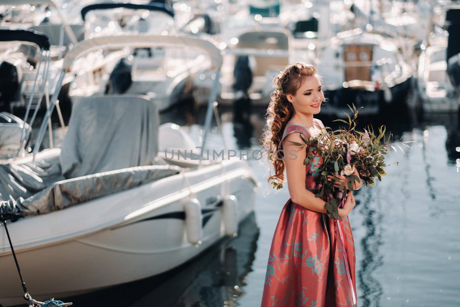 Young model girl in a beautiful dress with a bouquet of flowers on the beach in France. Girl with flowers in spring Provence on the French Riviera by Lobachad