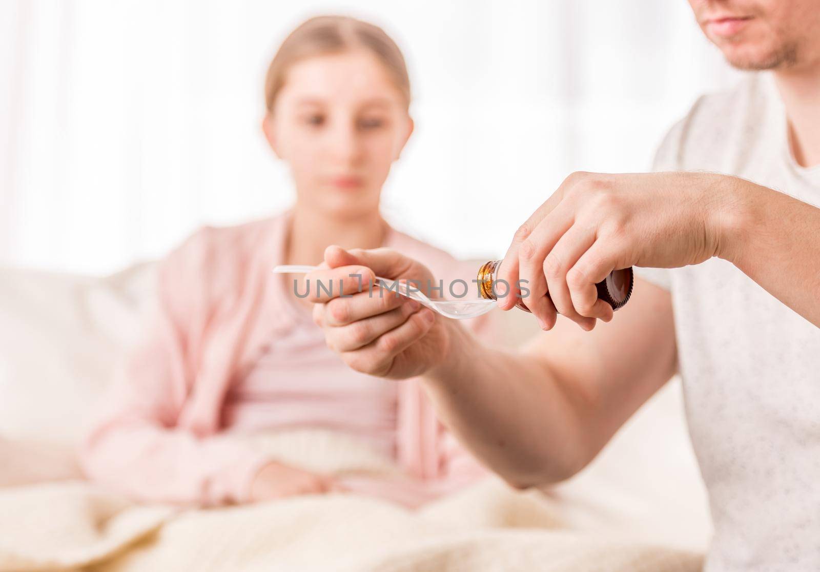 Loving father pouring effective medicine onto measuring spoon