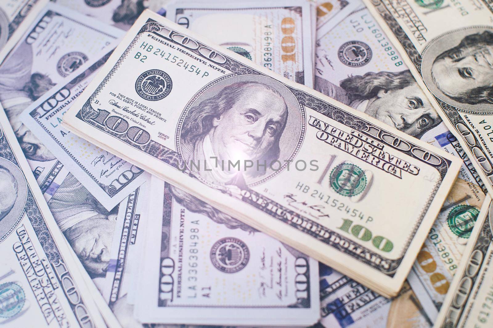 A stack of money. Heap of one hundred dollar bills on money background. Fake money. Shallow depth of field. Selective focus.