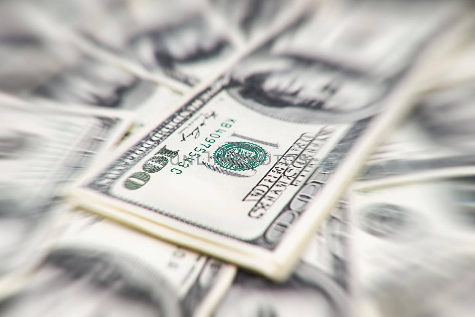 A stack of money. Heap of one hundred dollar bills on money background. Fake money. Shallow depth of field. Selective focus.