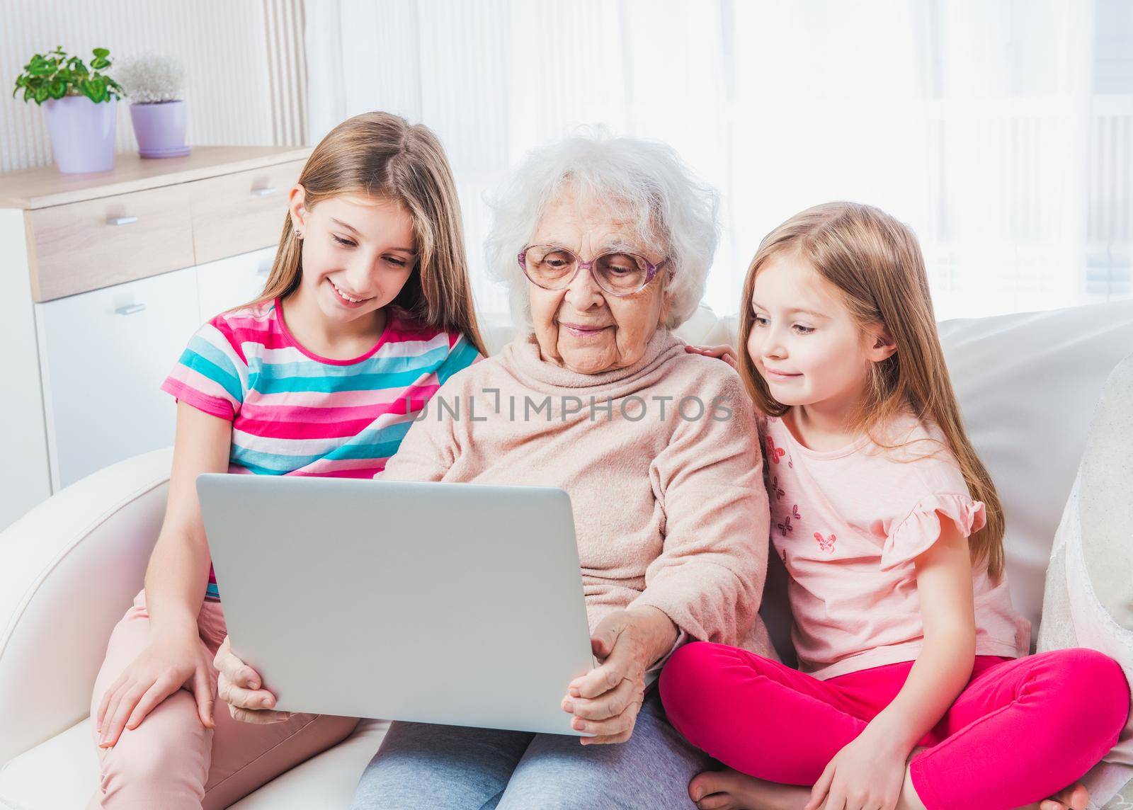 Great-grandmother with granddaughters watching laptop together