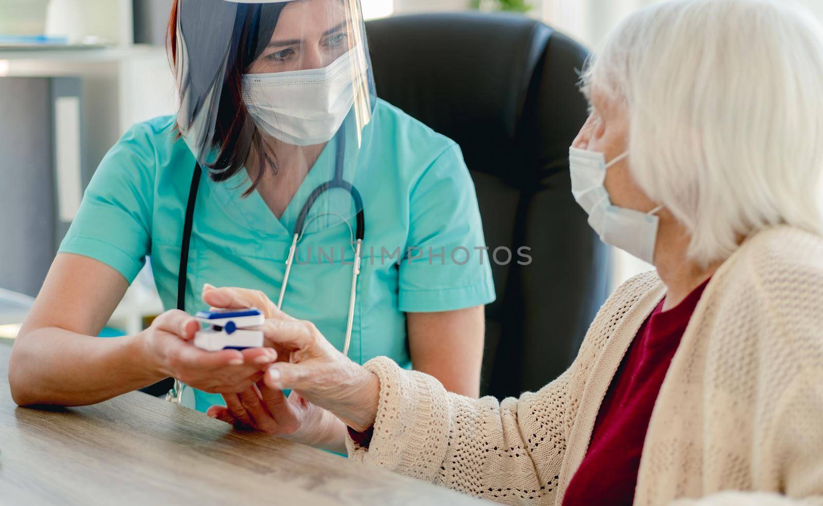 Elderly woman using pulse oximeter at appointment with doctor during coronavirus pandemic