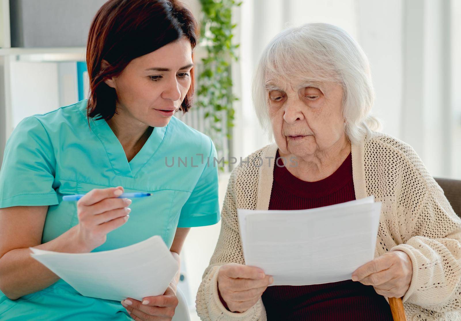 Nurse talking with elderly woman patient during visit in nursing home