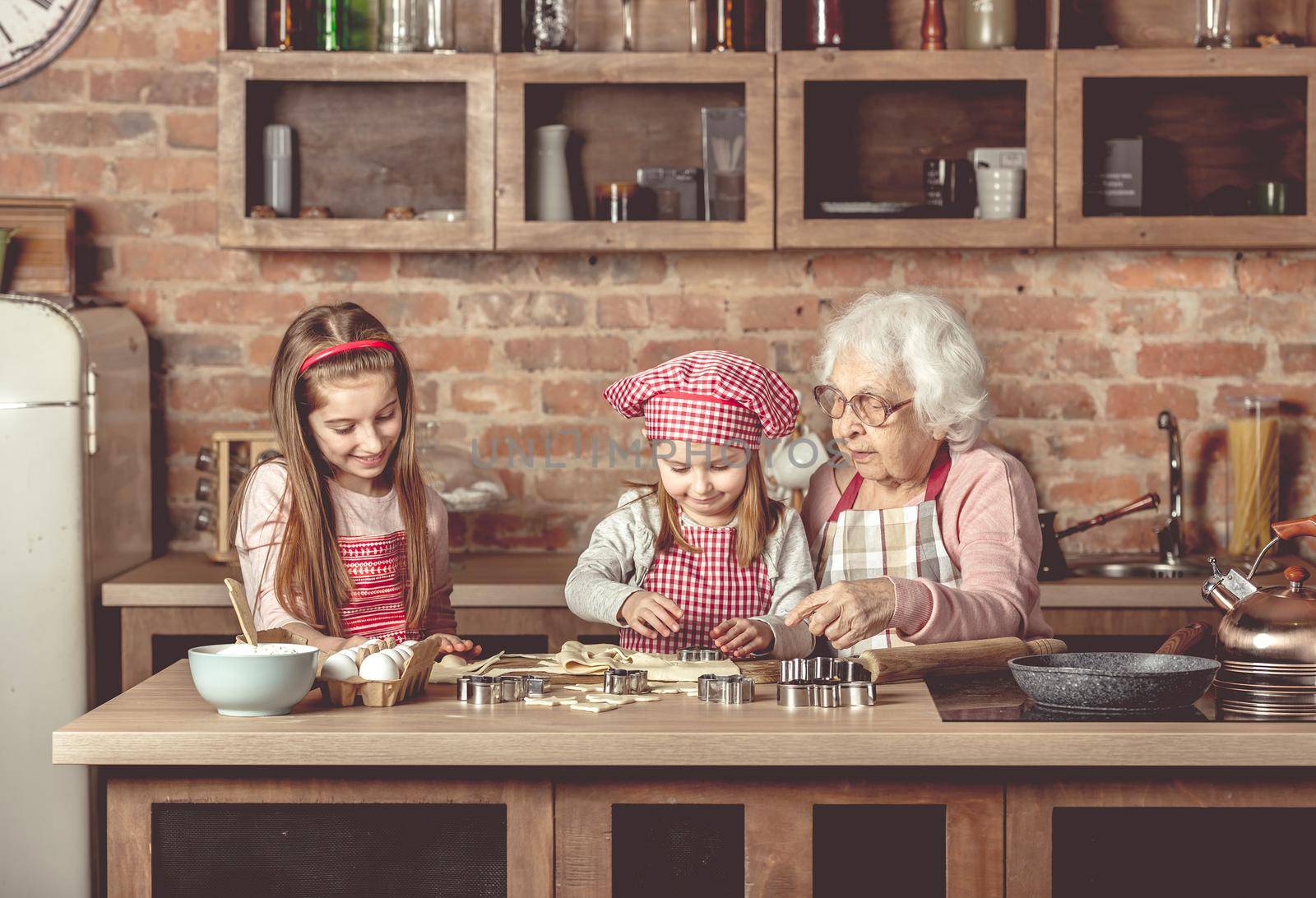Little granddaughters help granny to bake cookies by tan4ikk1