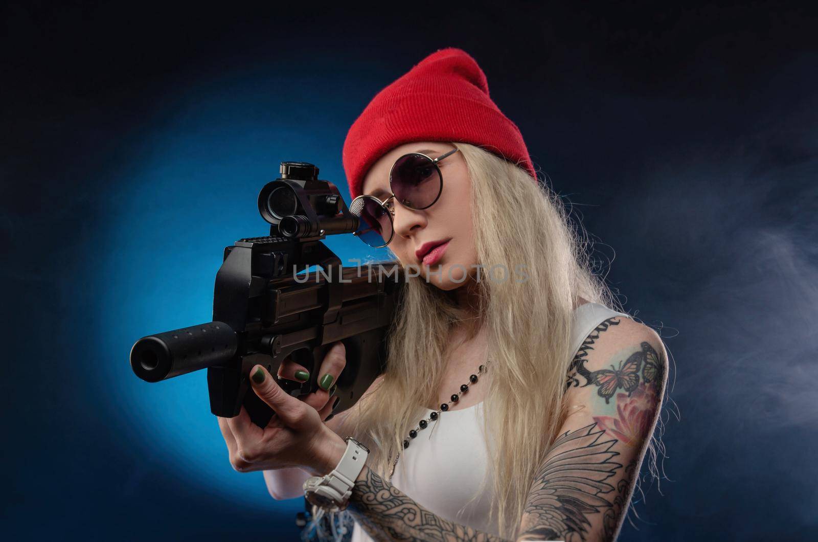 bright blonde in a red hat with a submachine gun on a dark background
