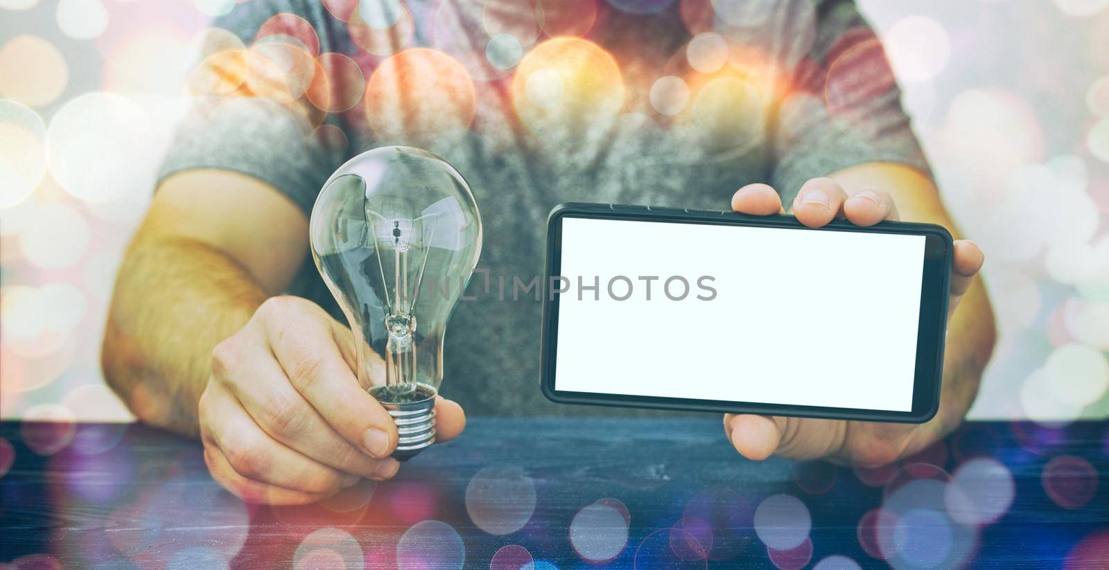 Mockup phone . A man holding a phone with a white screen and a light bulb, investment in ideas, investment in a startup. by Maximusnd