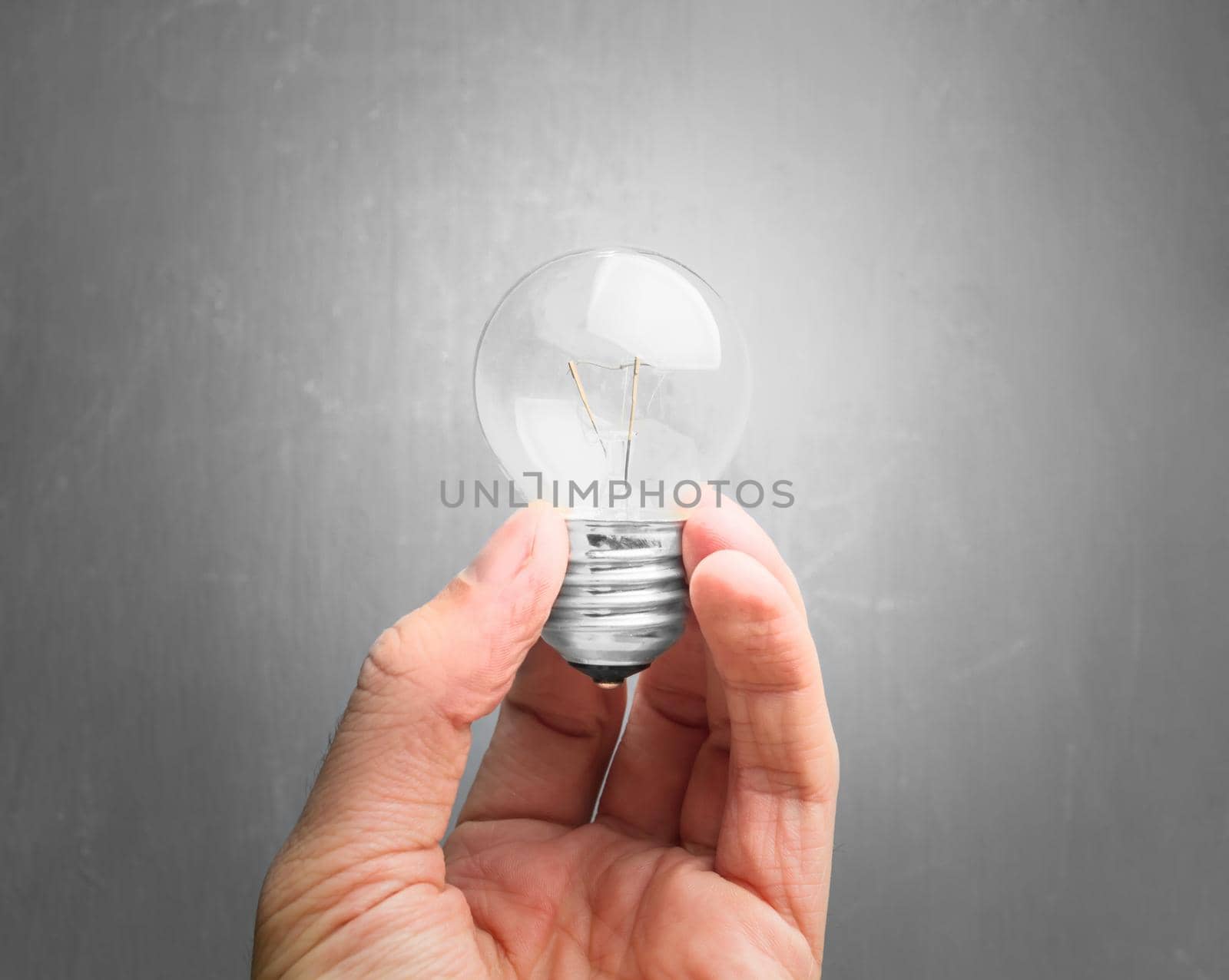 Light bulb in hand on gray background