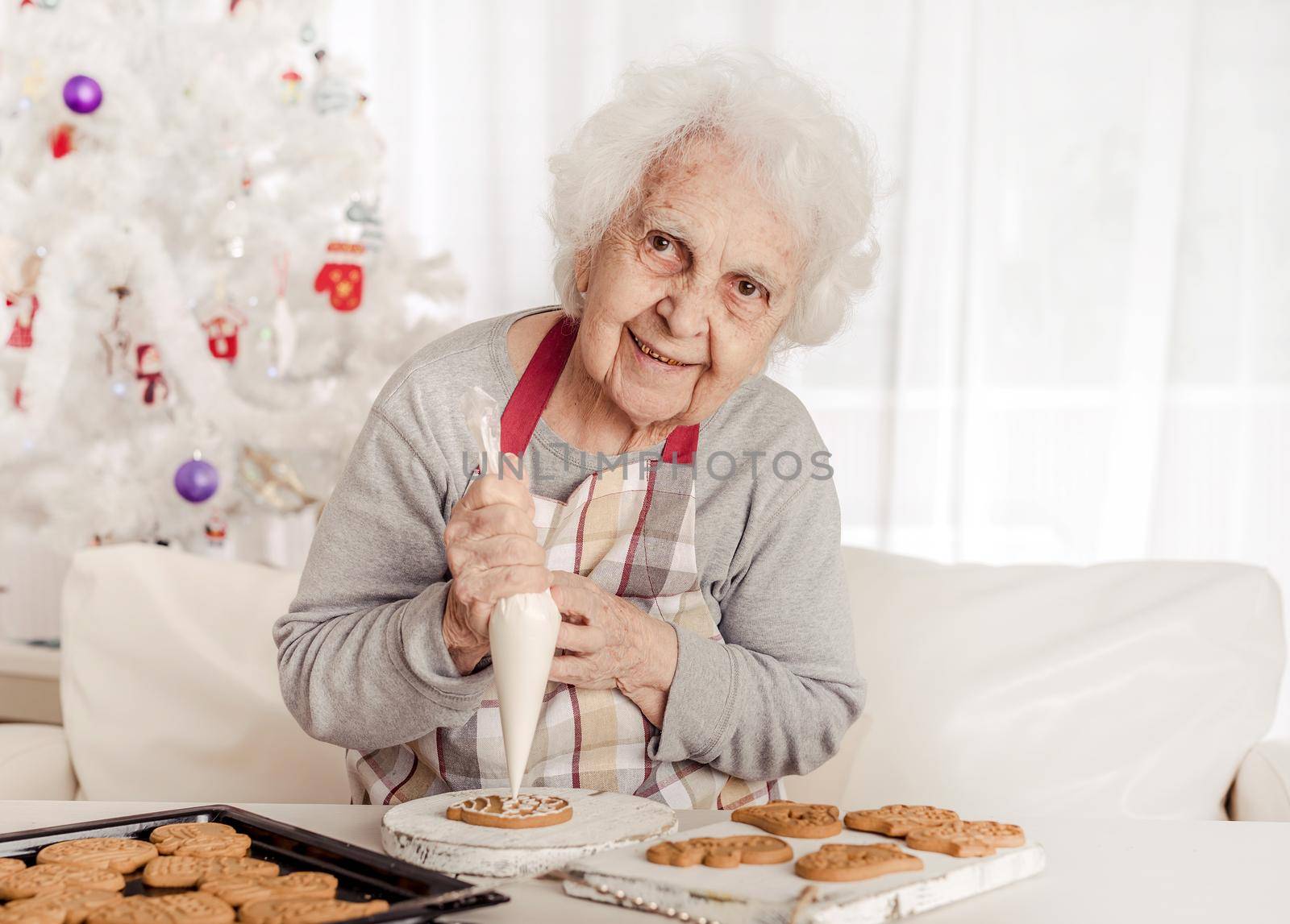 Elder woman soaking cream on Christmas cookies by tan4ikk1