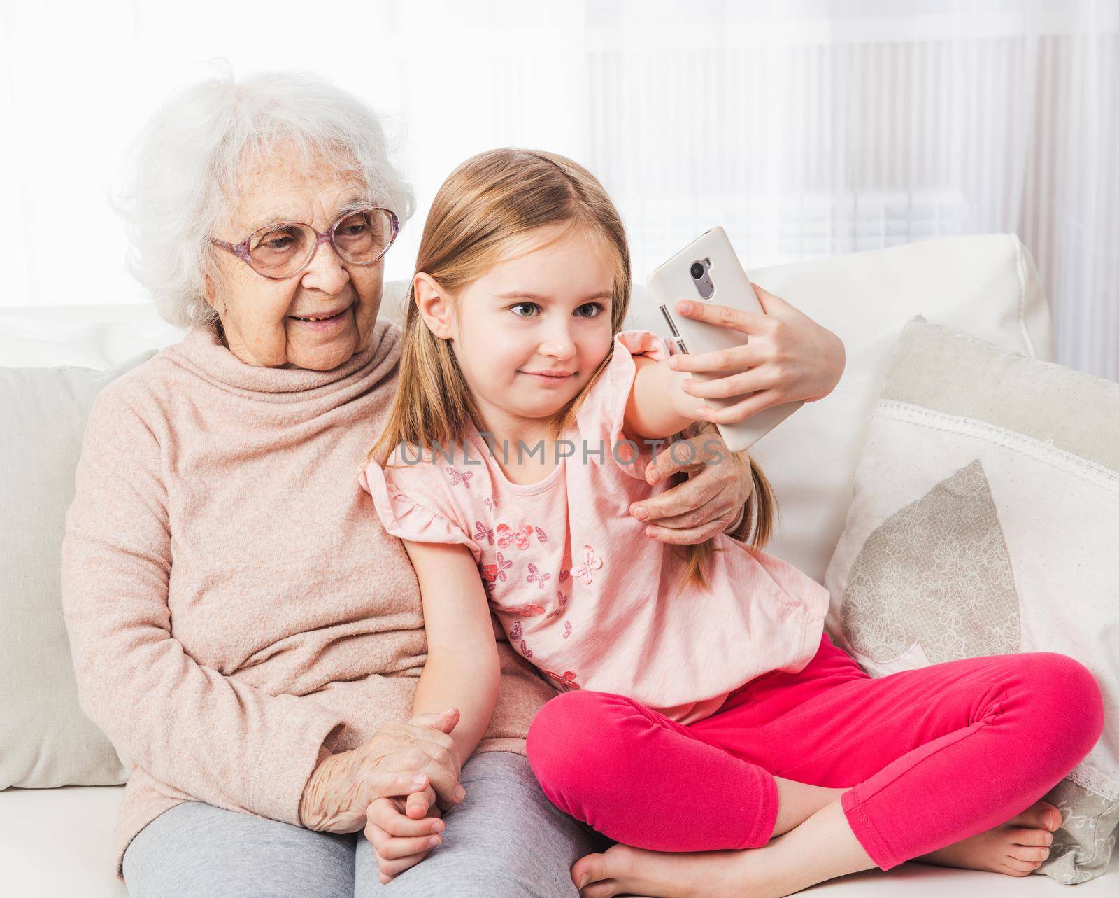 Little granddaughter taking selfie with great-grandmother