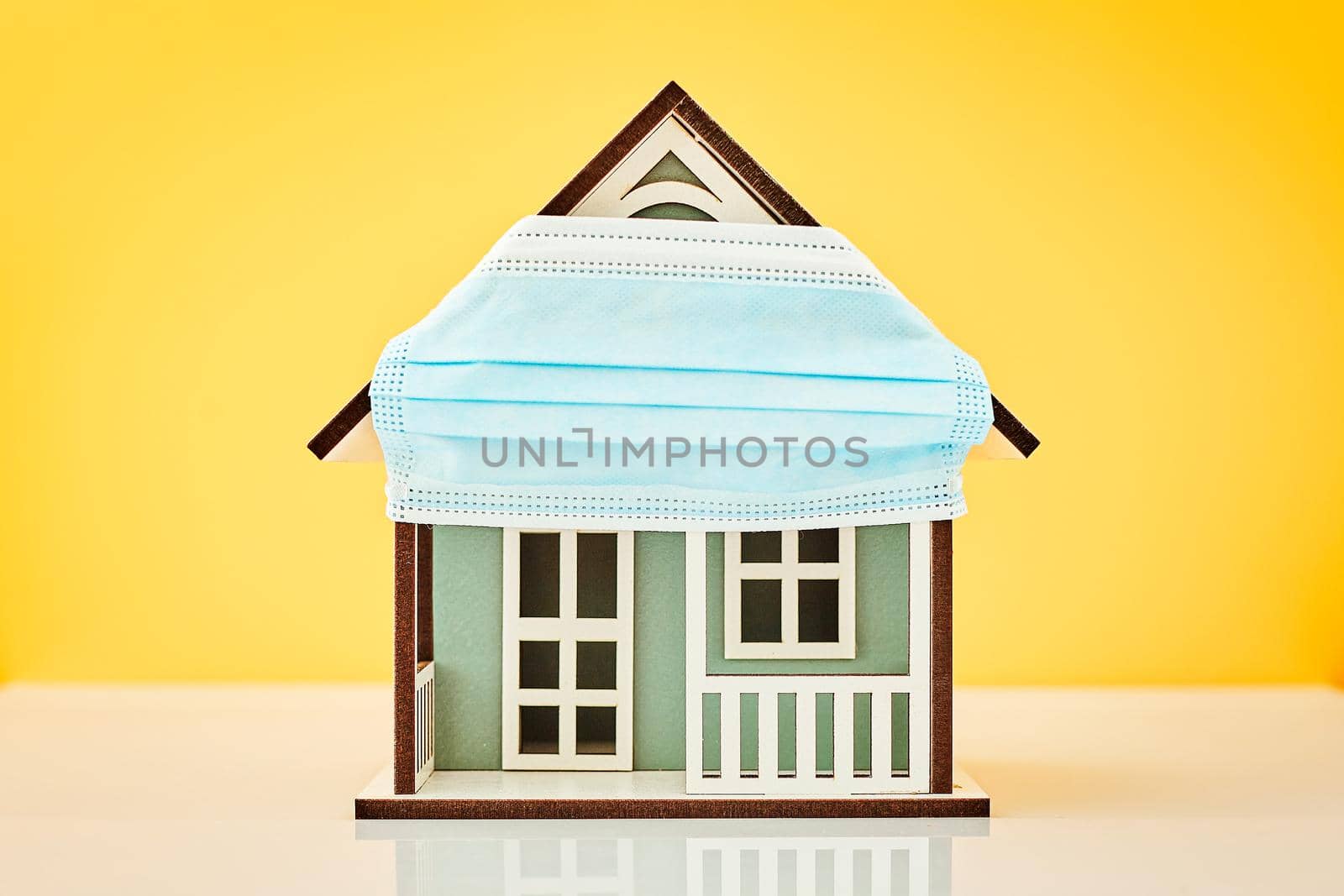 Model house wearing protective medical mask in yellow background