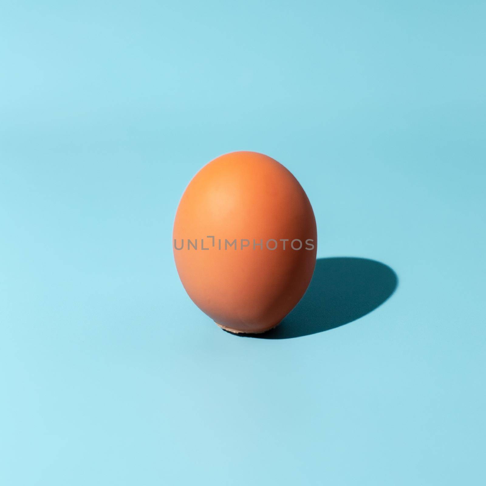 Egg over blue background. Sunshine with hard shadow. Minimal food concept by Maximusnd