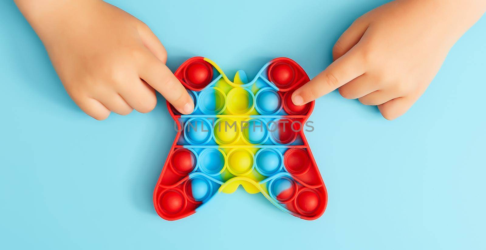 Trendy toy antistress. Anonymous child with colorful poppit game. Image of trendy Pop it fidget toy . Top view of the new sensory toy