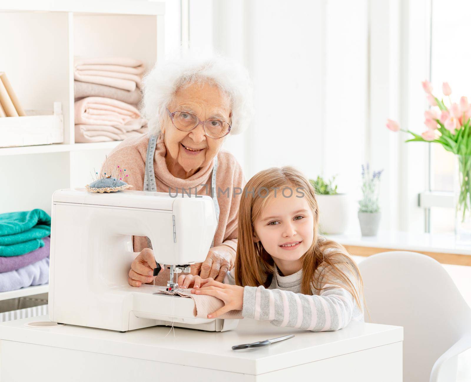 Grandmother teaching grandkid to sew by tan4ikk1