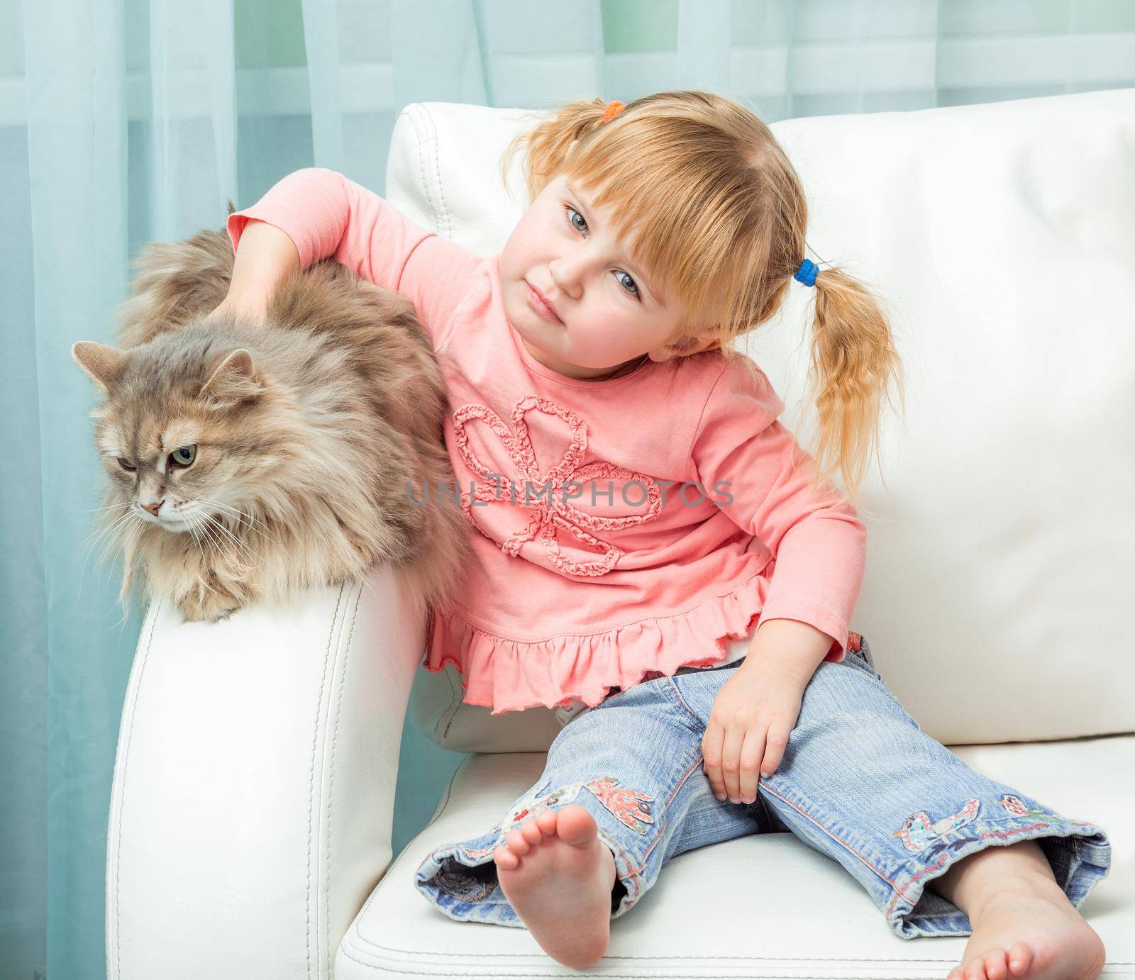 little cute girl with cat on white sofa