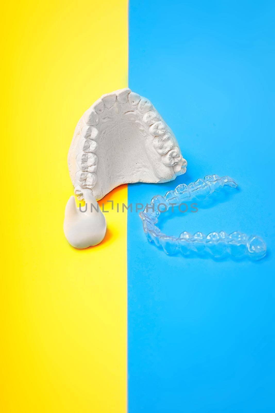 Orthodontic dental theme on blue and yellow background.Transparent invisible dental aligners or braces aplicable for an orthodontic dental treatment by Maximusnd