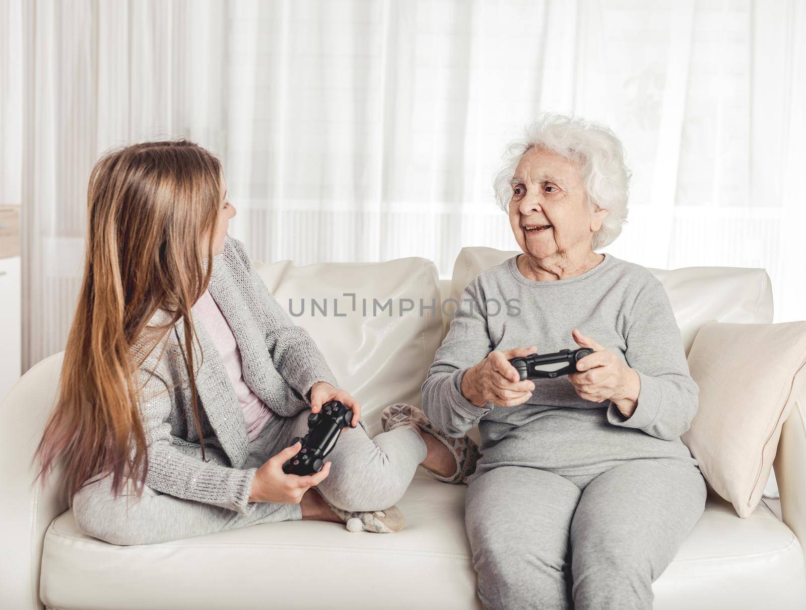 Grandmother with granddaughter playing games together with gamepads