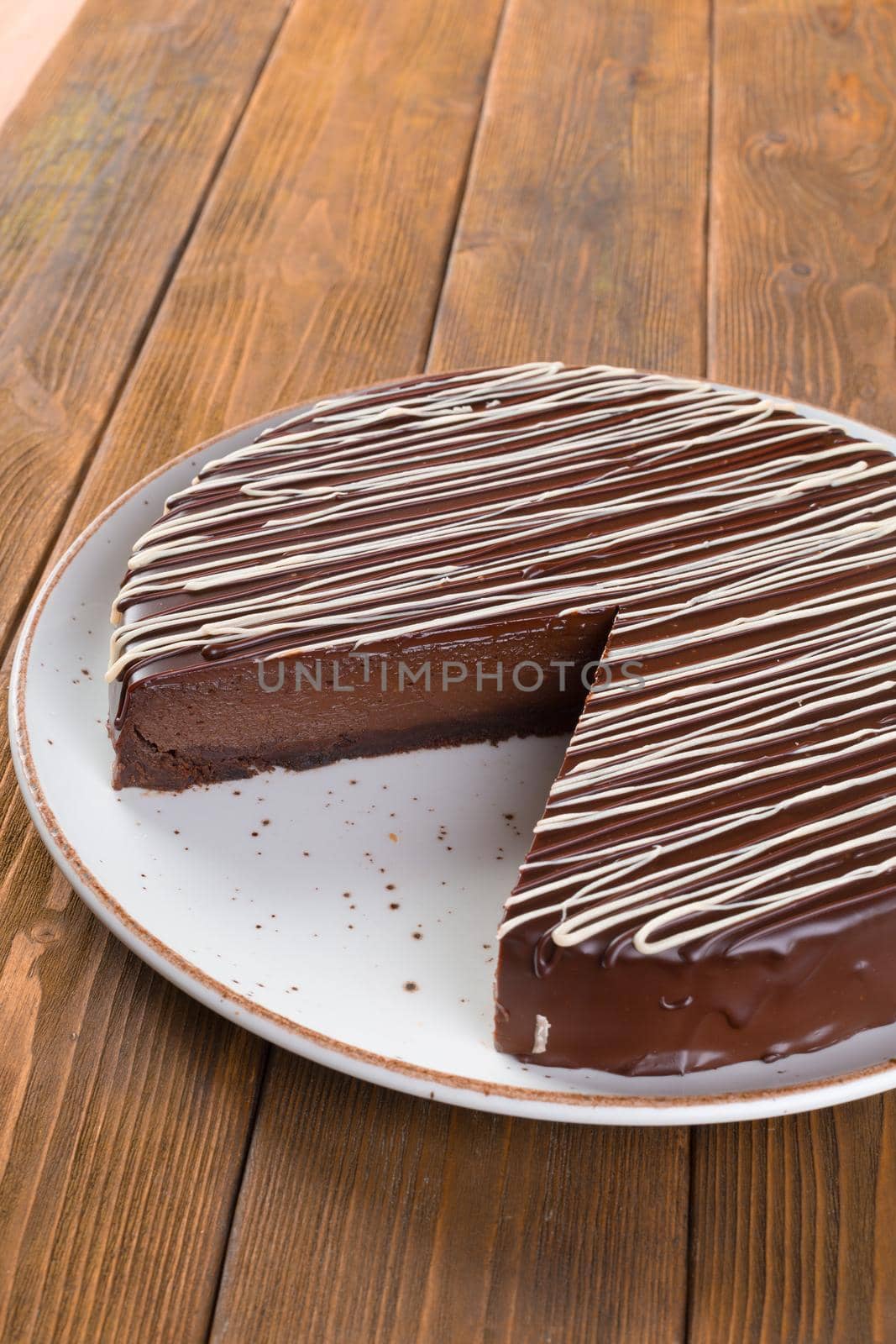 Cut chocolate cake on plate on wooden table by Fabrikasimf