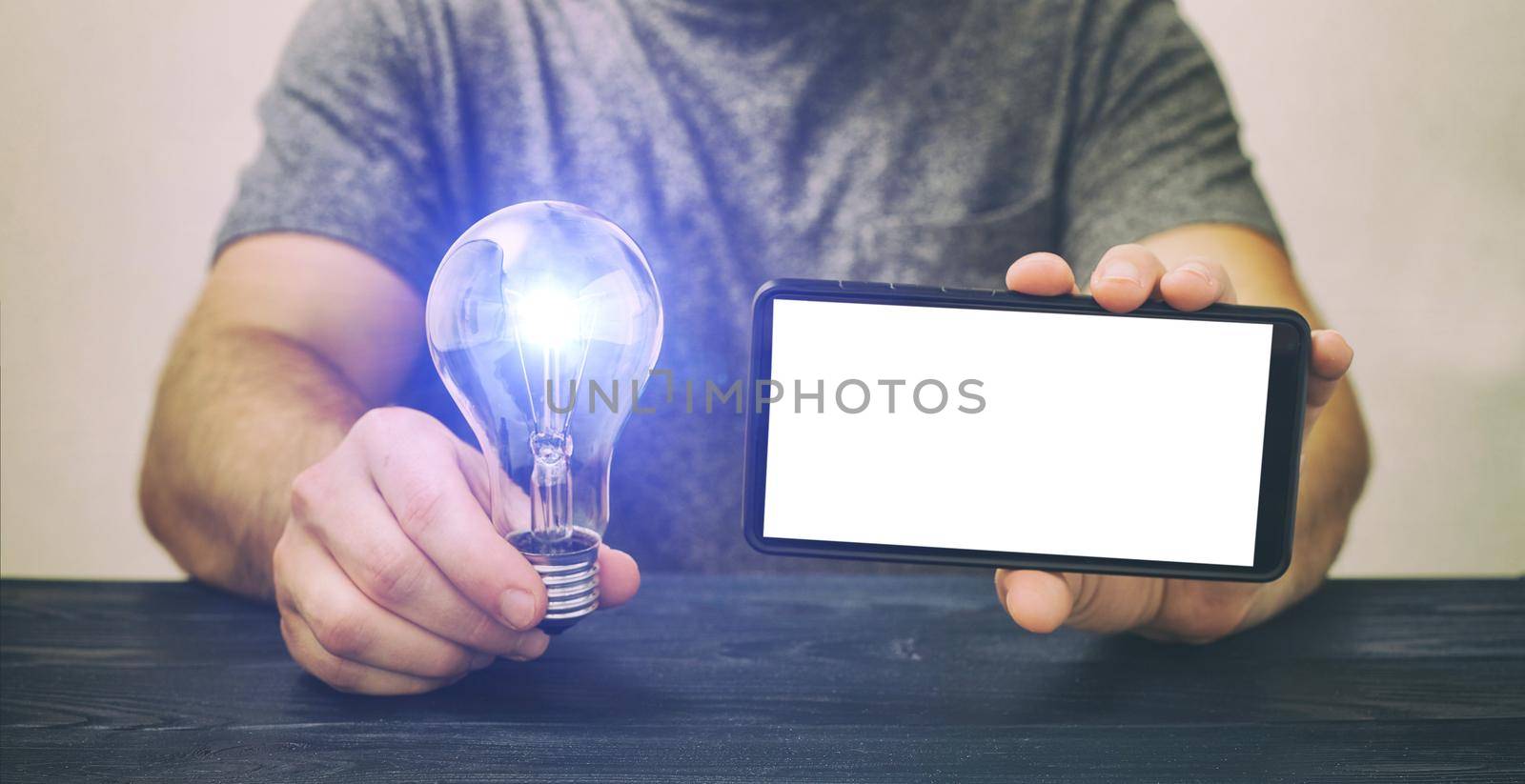 Mockup phone . A man holding a phone with a white screen and a light bulb, investment in ideas, investment in a startup.