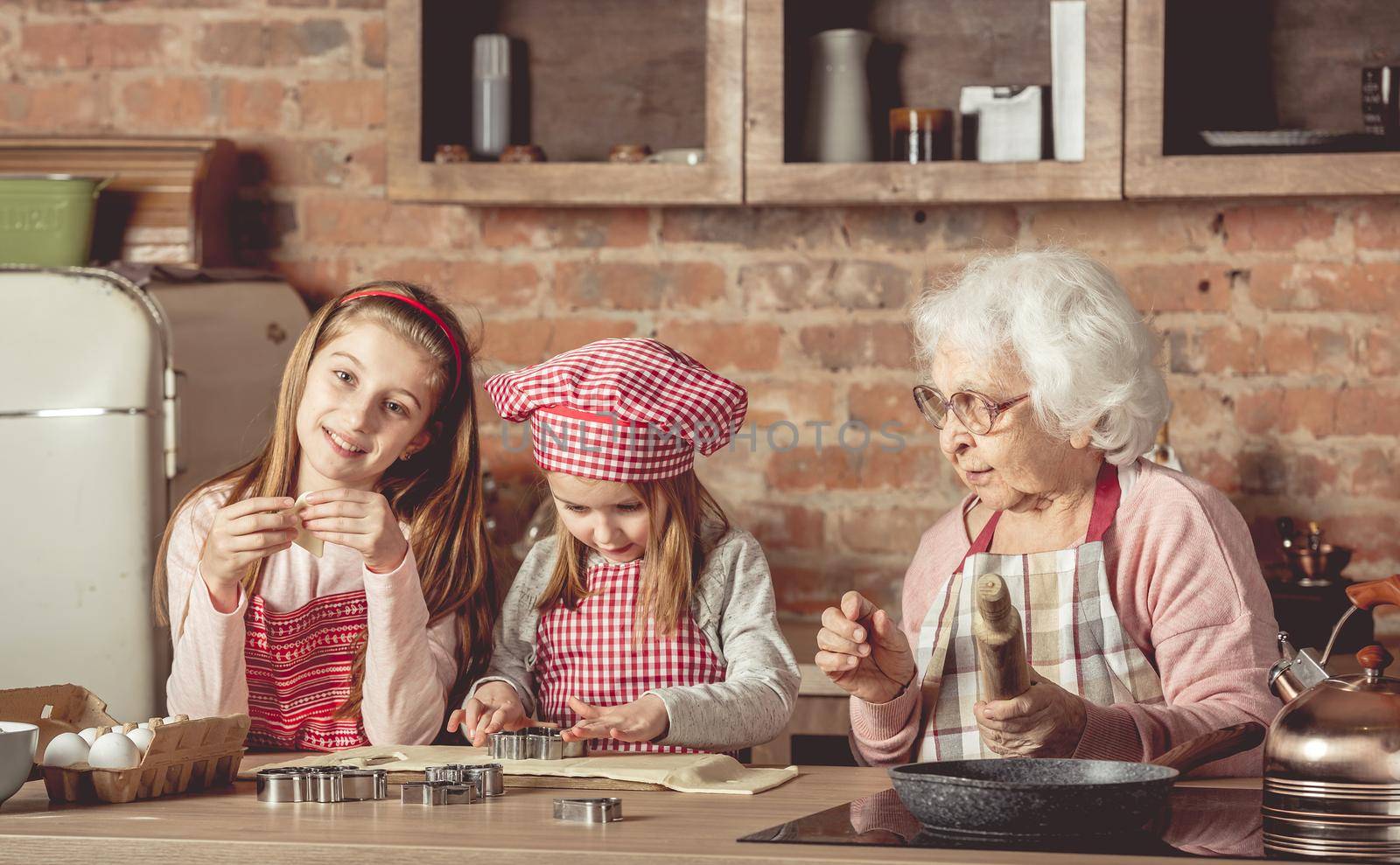 Little granddaughters help granny to bake cookies by tan4ikk1