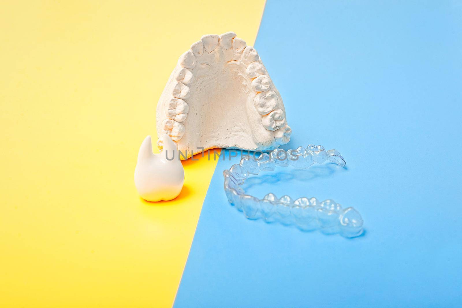 Orthodontic dental theme on blue and yellow background.Transparent invisible dental aligners or braces aplicable for an orthodontic dental treatment by Maximusnd